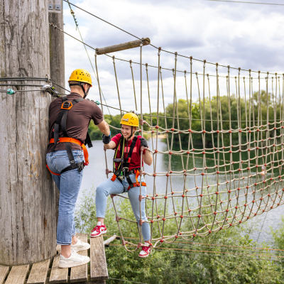 Lachende junge Frau steht an einem Kletterelement