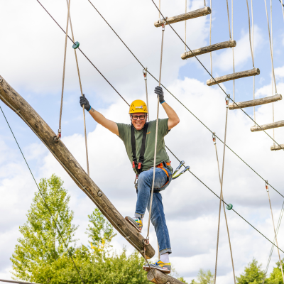 Mann in einem Kletterelement vor dem Himmel 