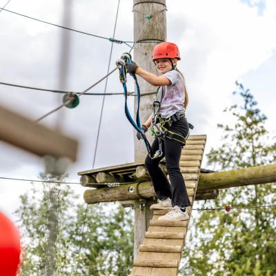 Kind steht auf einer Kletterleiter nach oben 
