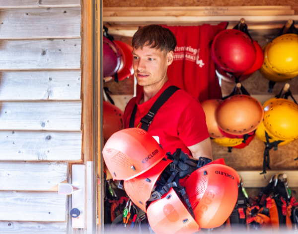 Junger Mann beim Kletterhelme herholen aus Materialh�tte