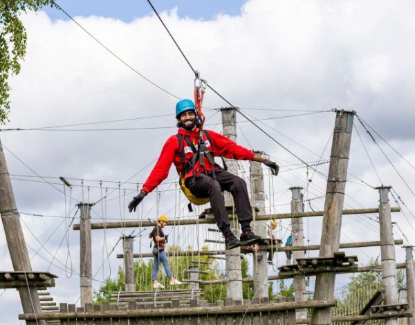 Junger Mann in einer Seilrutsche im Kletterpark